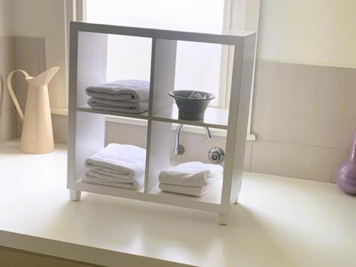 a white shelf with towels and a bowl on it at Belton Apartments-Hedge Cottage in Hobart
