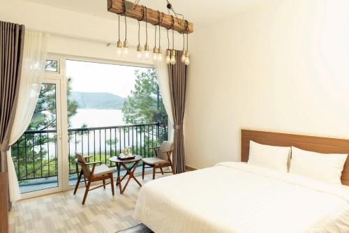 a bedroom with a bed and a balcony with a table and chairs at Romeo & Juliet Dalat Resort in Da Lat