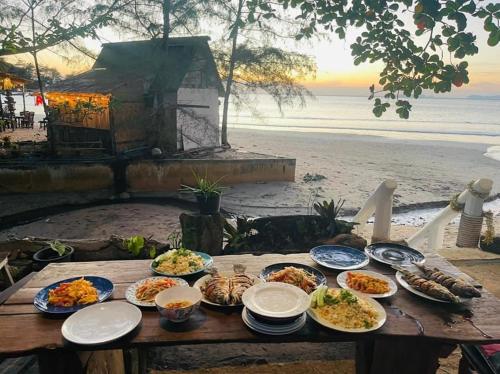 a picnic table with plates of food on a beach at Coconut Lanta Resort @Klong Dow beach in Krabi