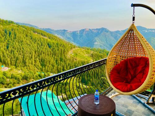een schommelstoel op een balkon met uitzicht op een berg bij Royal Green Valley View Mashobra in Shimla