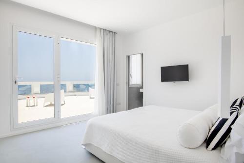 a white bedroom with a bed and a large window at Caiammari Boutique Hotel & Spa in Syracuse