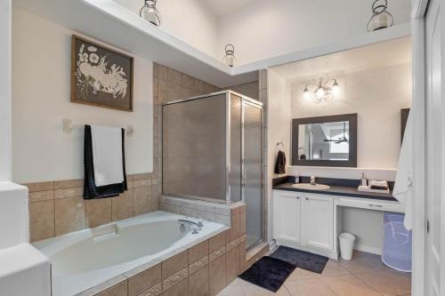 Un baño con bañera, lavabo y espejo. en Wonderful Weston Hills Villa SE Facing Pool, en Orlando