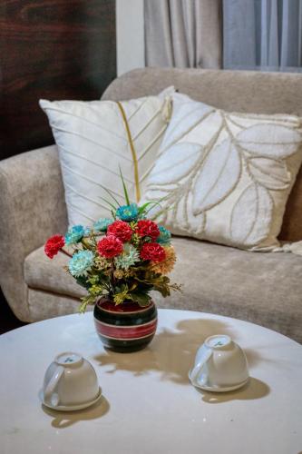 a vase with flowers on a table next to a couch at Hanoi Family Homestay in Hanoi
