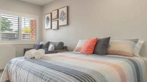 a bedroom with a large bed and a couch at Coasters 18 - steps from downtown Sawtell in Sawtell