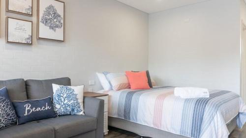 a small bedroom with a bed and a couch at Coasters 18 in Sawtell