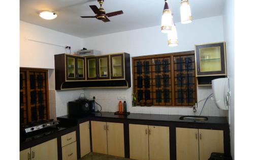 a kitchen with wooden cabinets and a ceiling fan at Ronne's Casa De Piscina Privada 3BHK VILLA in Verla