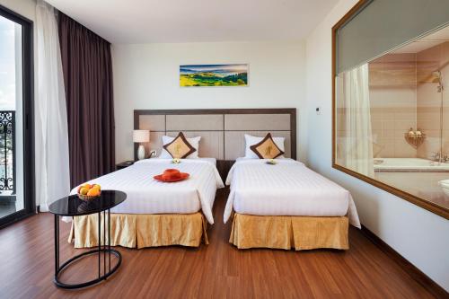 a hotel room with two beds and a tub at Daphovina Hotel in Nha Trang
