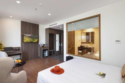 a bedroom with a white bed and a living room at Daphovina Hotel in Nha Trang
