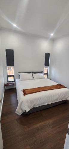 una camera bianca con un grande letto e pavimenti in legno di Glossy Black Cabin a Parndana