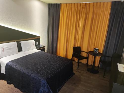 a hotel room with a bed and a table and chairs at Hotel Dubái in Texcoco de Mora