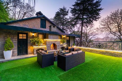 a house with a lawn with couches and a fireplace at StayVista at Paris Villa with Pvt Pool & Valley View in Kasauli