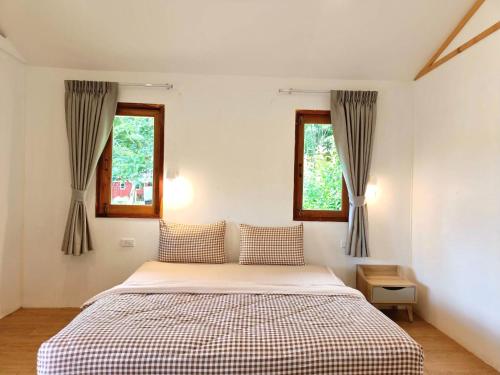 a bedroom with a bed and two windows at Baan Suan Rojjana in Muak Lek District