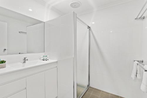 een witte badkamer met een douche en een wastafel bij Unit 1 Sunbird on Lamond in Airlie Beach