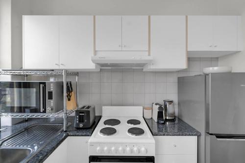 a kitchen with white cabinets and a stove top oven at Kadina Harbourside Studio - A Cosy Panoramic Gem in Sydney