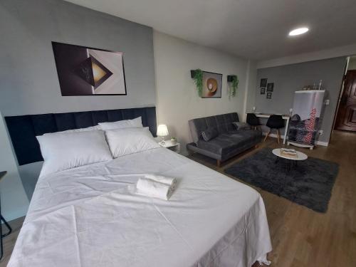 1 dormitorio con 1 cama blanca grande y 1 sofá en Lindo FLAT47 metrô e VLT da CARIOCA - LAPA, en Río de Janeiro