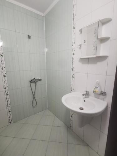 a white bathroom with a sink and a shower at Студиa Блу минута от плажа in Pomorie