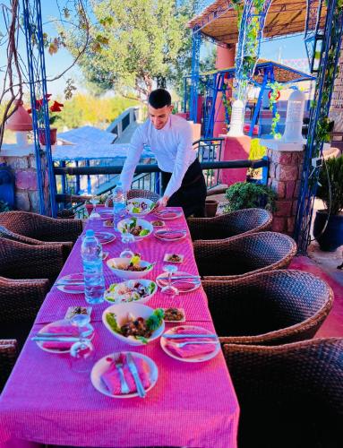 a man standing in front of a table with plates of food at maison d'hôtes yamine in Beni Mellal