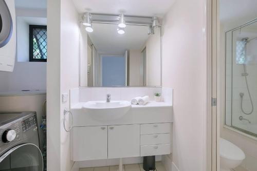 uma casa de banho branca com um lavatório e um espelho em Centro at Toowong - Modern Spacious Living with Pool em Brisbane