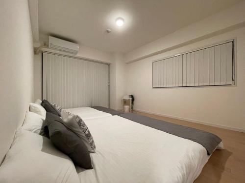 a bedroom with a large white bed and a window at b hotel M's lea - Beautiful Modern Apt City Center for 10Ppl in Hiroshima