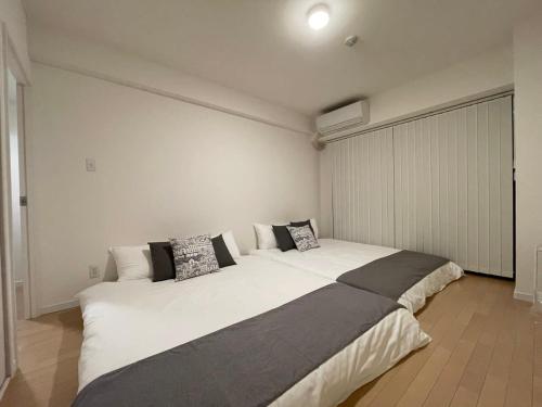 1 dormitorio con 1 cama blanca grande con almohadas en bHOTEL M's lea - Modern Spacious Apartment Beside Peace Park 10 ppl, en Hiroshima