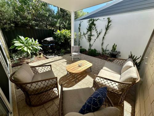 a patio with a table and chairs and an umbrella at Serenity by the Sea in Busselton
