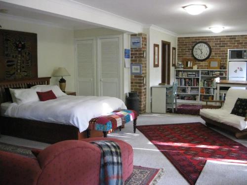 a bedroom with a bed and a couch and a clock at Warriwul Farmland Rural Retreat BnB, Curramore/Jamberoo in Jamberoo