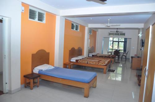 a room with three beds in a room with at Vinayaka Deluxe Lodge in Kushālnagar