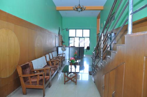 a hallway with chairs and a table with flowers on it at Vinayaka Deluxe Lodge in Kushālnagar
