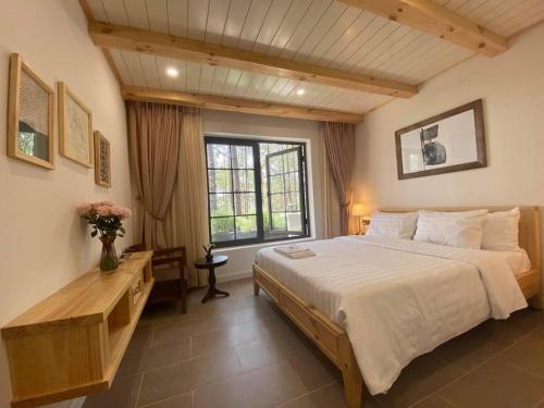 a bedroom with a large bed and a window at Biệt Thự Đà Lạt View Đẹp - Gần Chợ Đêm in Xuan An