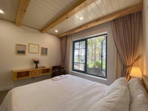 a bedroom with a large white bed and a window at Biệt Thự Đà Lạt View Đẹp - Gần Chợ Đêm in Xuan An