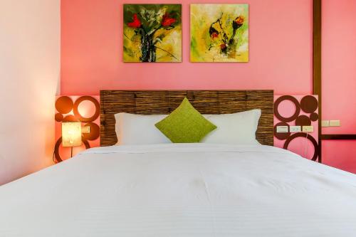 a bedroom with a white bed with two paintings on the wall at Southern Sun Homestay North in Kenting