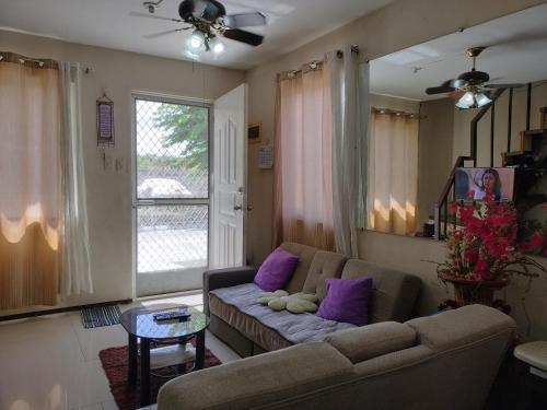 a living room with a couch and purple pillows at Eurich Furnished Unit 1 in Butuan