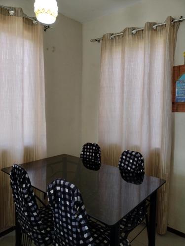a dining room table with chairs in front of curtains at Eurie's Furnished Unit in Butuan