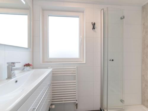 韋默爾丁厄的住宿－Modern chalet with decorative fireplace in Zeeland，带淋浴和盥洗盆的白色浴室