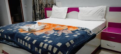 a bed with a blue and white comforter on it at Radhe Radhe Guest House in Dehradun