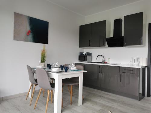 a kitchen with a white table and some chairs at Tarasy Anastazewa in Anastazewo