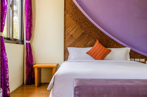 a bedroom with a large bed with a purple headboard at Southern Sun Homestay North in Kenting