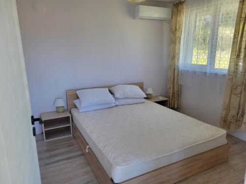 een witte slaapkamer met een bed met blauwe kussens en een raam bij Villa Mimi in Varna
