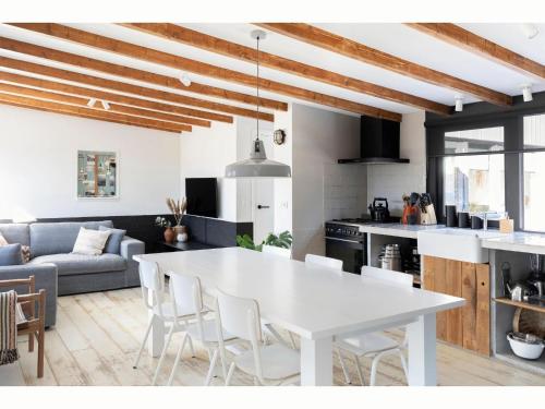 eine Küche und ein Wohnzimmer mit einem weißen Tisch und Stühlen in der Unterkunft Unique luxury detached holiday home by the sea in Callantsoog