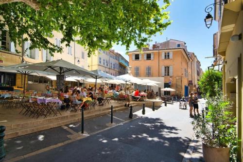 um grupo de pessoas sentadas em mesas sob guarda-chuvas em uma rua da cidade em Albertas Furnished studio em Aix-en-Provence