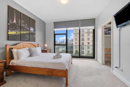 1 dormitorio con cama y ventana grande en East Melbourne 2BR Apartment, en Melbourne