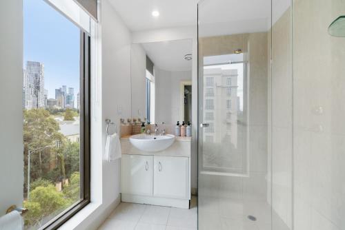 a bathroom with a sink and a shower with a window at East Melbourne 2BR Apartment in Melbourne