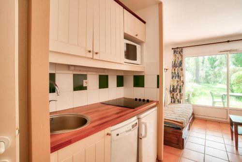 une cuisine avec un évier et un micro-ondes dans l'établissement Le Domaine du Golf de Pinsolle - maeva Home - Appartement 2 pièces 5 personnes - Confort MAE-7414, à Soustons