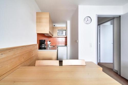 une cuisine avec des armoires en bois et une horloge au mur dans l'établissement Résidence Les Gémeaux - maeva Home - Studio 4 Personnes - Confort MAE-7474, à La Plagne Tarentaise