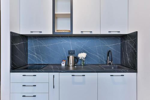 a kitchen with white cabinets and a black counter top at Hotel Boka in Kotor