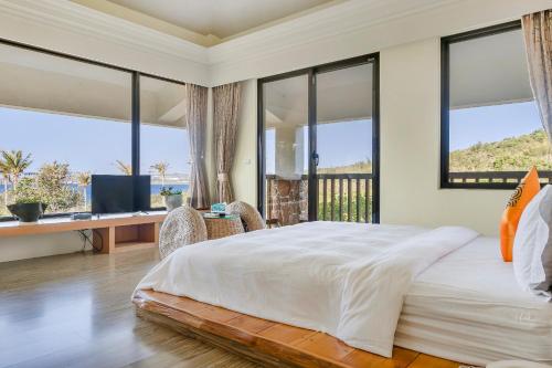 a bedroom with a large bed with a desk and windows at Southern Sun Homestay North in Kenting