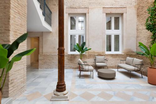 een binnenplaats met stoelen, een paal en ramen bij Magno Apartments Almansa in Sevilla