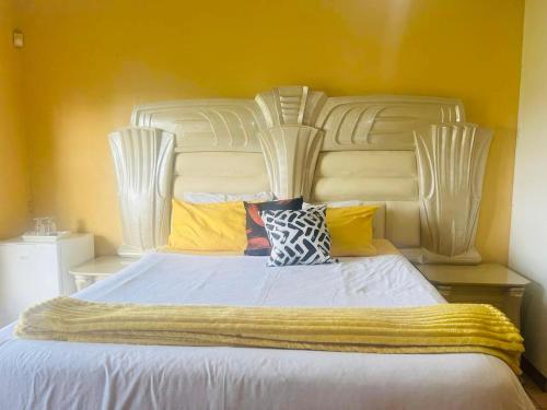 a large white bed with colorful pillows on it at Eliza Guest House in Empangeni