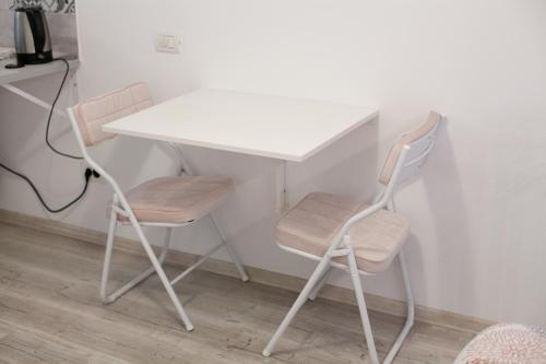 een witte tafel en 2 stoelen naast een bureau bij Cozy Studio Apartment in Arad City Center in Arad