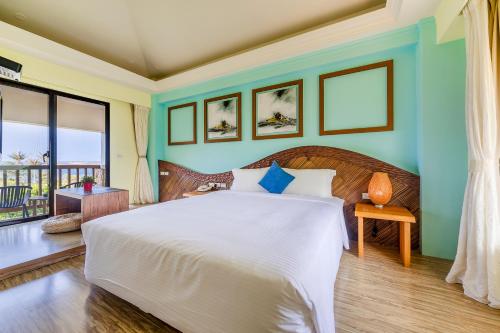 um quarto com uma grande cama branca com paredes azuis em Southern Sun Homestay North em Kenting